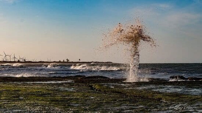 [Água espirrando da formação rochosa Suspiro da Baleia]